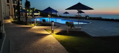 a swimming pool with chairs and umbrellas at night at Susi`s TheView Luxuriöse Ferienwohnung mit fantastischem Meerblick in Hurghada