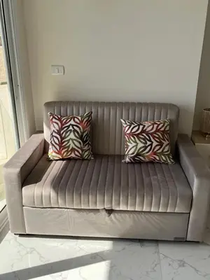 a brown leather couch with pillows in a living room at Benashti Hurghada apartment 407 in Hurghada