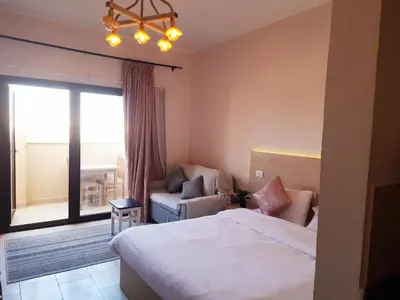 a bedroom with a bed and a chair and a window at ALDAU Heights Mountain View in Hurghada