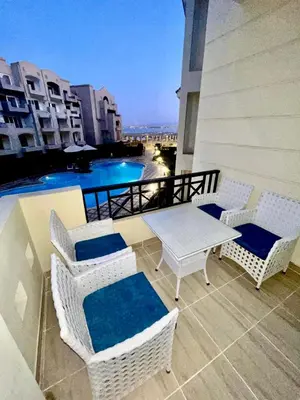 a balcony with wicker chairs and a table and a pool at Sahl Hasheesh, El Andalous by sea and pool view, private beach in Hurghada