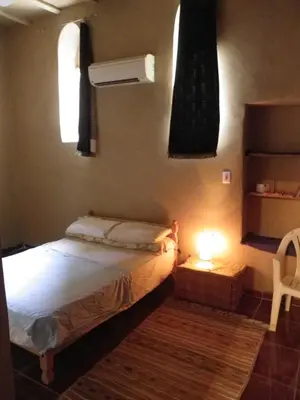 a small bedroom with a bed and a lamp at maison luxor in Al Aqālitah