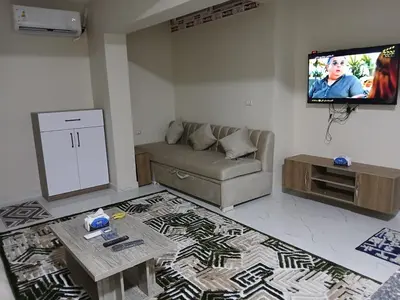 a living room with a couch and a flat screen tv at Hossam Cozy Apartment El Hadaba Sheraton in Hurghada