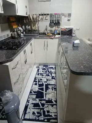 a kitchen with white cabinets and a black and white rug at Hossam Cozy Apartment El Hadaba Sheraton in Hurghada