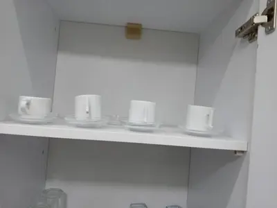 a white shelf with cups and saucers on it at Hossam Cozy Apartment El Hadaba Sheraton in Hurghada