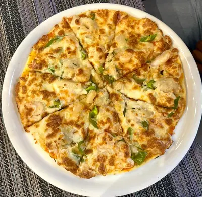 a pizza on a white plate on a table at Juliana Beach Hurghada in Hurghada