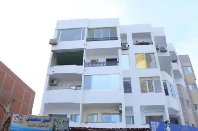 a tall white building with people on the balconies at Hossam Apartment Marina Area Hurghada in Hurghada