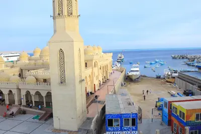 a large building with a clock tower next to the water at Hossam Apartment Marina Area Hurghada in Hurghada