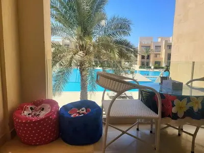 a balcony with a table and chairs and a palm tree at Mangroovy Serinity 2br pool view in Hurghada