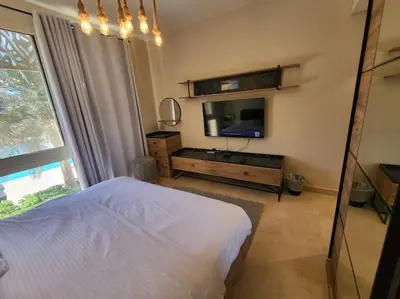 a bedroom with a bed and a flat screen tv at Mangroovy Serinity 2br pool view in Hurghada