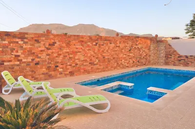 a swimming pool with two lawn chairs next to a brick wall at Sultan Guest House in Luxor
