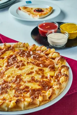 a pizza on a table with other plates of food at Al Fanar Azur Hotel in Suwhaj