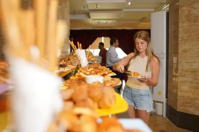 a woman standing in front of a table with a plate of food at Al Fanar Azur Hotel in Suwhaj