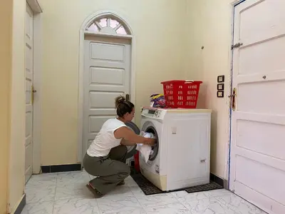 a woman loading a washing machine in a room at La Veranda \u967d\u53f0 in Aswan