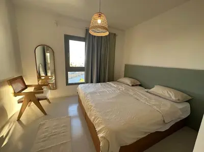 a bedroom with a bed and a chair and a mirror at Penthouse 3 Bedrooms in Swan Lake ElGouna in Hurghada