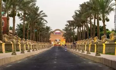 a street with palm trees and a bus driving down a road at شاليه في منتجع ميراج in Hurghada