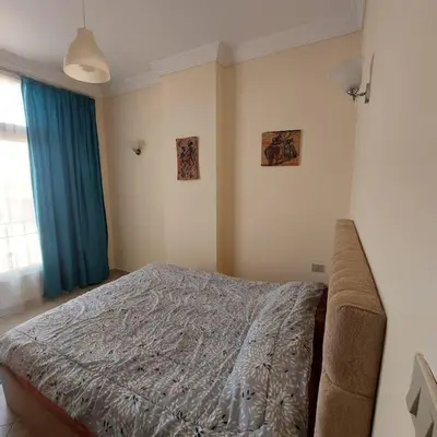 a bedroom with a bed and a blue curtain at Mamsha view 1 bedroom flat beside Russian consulate in Hurghada