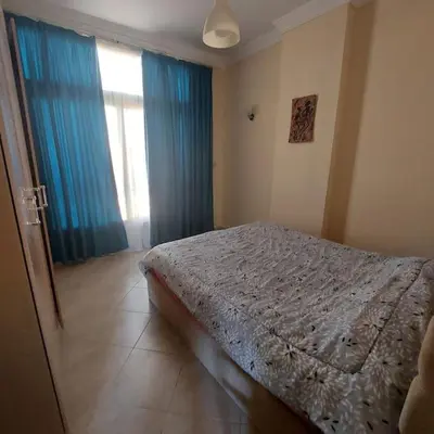a bedroom with a bed and a window with blue curtains at Mamsha view 1 bedroom flat beside Russian consulate in Hurghada