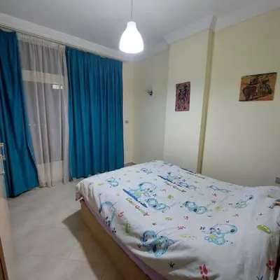 a bed in a bedroom with blue curtains at Mamsha view 1 bedroom flat beside Russian consulate in Hurghada