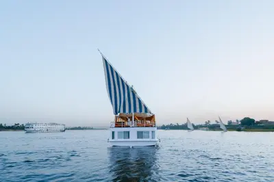 a boat in the water with a sail on the water at Turquoise Dahabiya , 3,4,7 nights sailing between Luxor and Aswan in Luxor