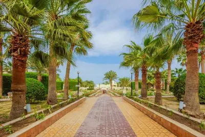 a walkway with palm trees in a park at Salvatore Rooms- All Inclusive in Hurghada