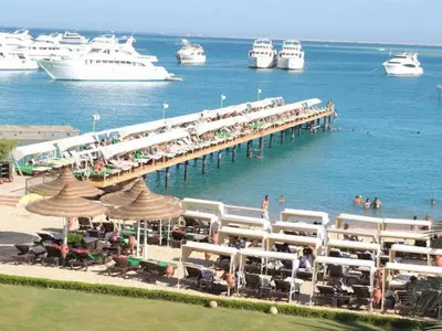 a pier with tables and chairs and boats in the water at Salvatore Rooms- All Inclusive in Hurghada