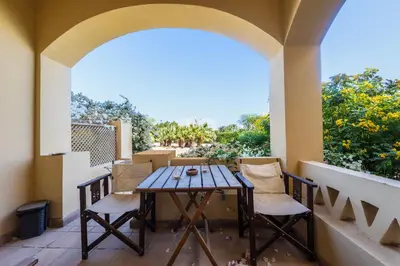 a table and chairs on a balcony with a window at Cozy Studio Ground floor in Upper Nubia in Hurghada