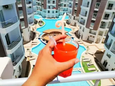 a person holding a drink in front of a city at Hotel Room in Aqua Palms Hurghada in Hurghada