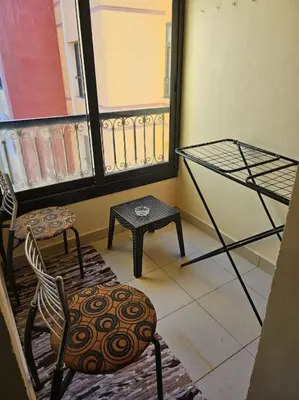 a room with a balcony with a bed and a chair at Esplanada flat with free beach, no single men in Hurghada