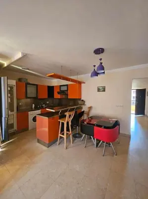 a kitchen with orange cabinets and a table and chairs at Esplanada flat with free beach, no single men in Hurghada