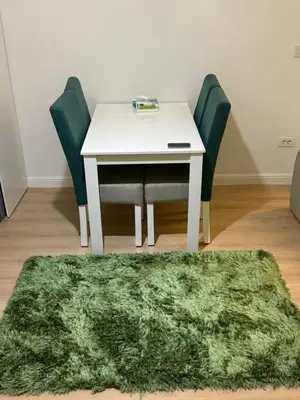 a white table with chairs and a green rug at Luxurious heart flat in Hurghada