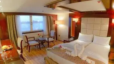 a bedroom with a bed and a table and a room at Sofia Nile Cruise Luxor & Aswan in Luxor