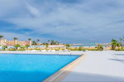 a swimming pool with a view of the beach and buildings at Scanddic Resort Hurghada in Hurghada