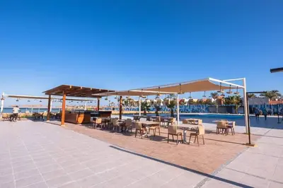 a patio with tables and chairs next to a pool at Scanddic Resort Hurghada in Hurghada