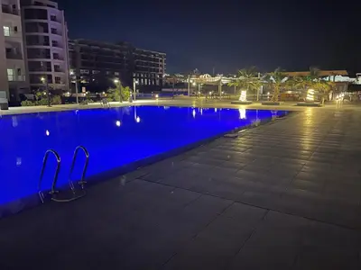 a blue swimming pool at night with buildings at Scanddic Resort Hurghada in Hurghada
