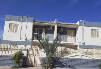 a white house with a palm tree in front of it at Villa Sara Touristic Center in Hurghada