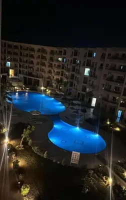 a group of pools in a large building at night at princess apartments in Hurghada