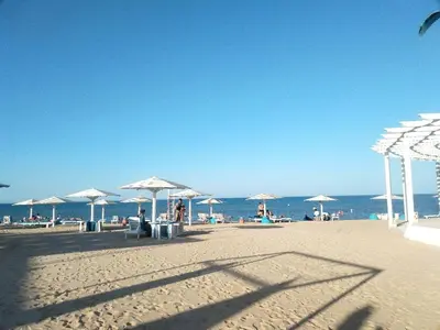 a beach with umbrellas and chairs and the ocean at Selena Bay Luxury Sea View 1BR Apartment, Private Beach and Pool in Hurghada