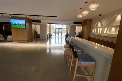 a lobby with a bar with chairs and a flat screen tv at Selena Bay Luxury Sea View 1BR Apartment, Private Beach and Pool in Hurghada