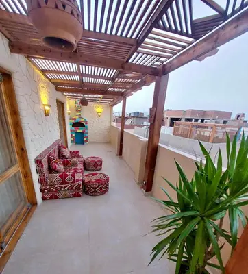 a patio with two chairs and a wooden pergola at Klimatyczny apartament na dachu w sercu Hurghady in Hurghada