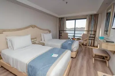 a hotel room with two beds and a desk at Nile Cruise 3 Nights Aswan to Luxor Sightseeing Included in Nag` el-Ramla