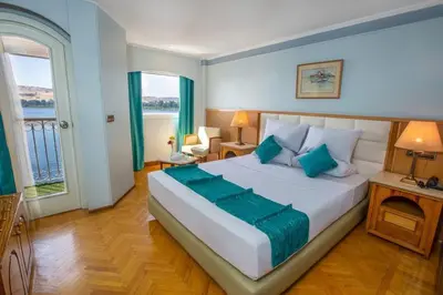a bedroom with a large white bed with blue pillows at Nile Cruise 3 Nights Aswan to Luxor Sightseeing Included in Nag` el-Ramla