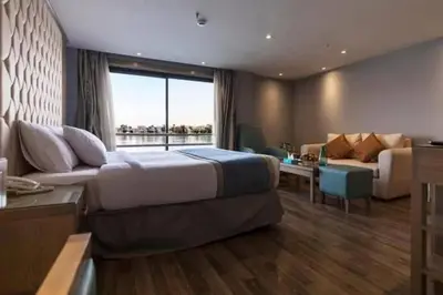 a hotel room with a large bed and a couch at Nile Cruise 3 Nights Aswan to Luxor Sightseeing Included in Nag` el-Ramla