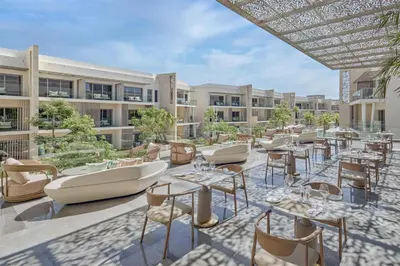 an outdoor patio with tables and chairs and a building at Doubletree By Hilton Mangroovy El Gouna Resort in Hurghada