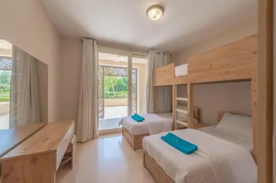a bedroom with two bunk beds and a desk and a window at Elegant apartment with pool and beach access in Hurghada