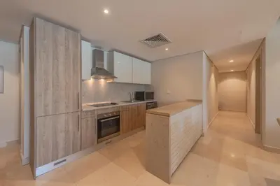 a large kitchen with white walls and wooden cabinets at Elegant apartment with pool and beach access in Hurghada