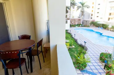 a room with a table and chairs and a swimming pool at El Andalous Sea View Apartment Sahl Hasheesh in Hurghada