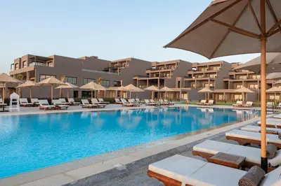 a large swimming pool with lounge chairs and an umbrella at Sentido Naga Bay - Adults friendly in Hurghada