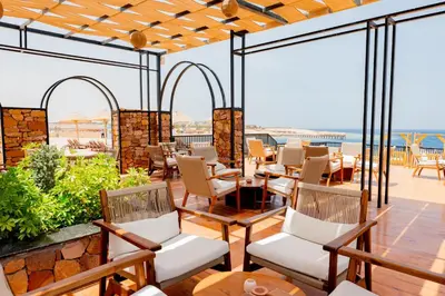 a patio with chairs and tables and the ocean at Sentido Naga Bay - Adults friendly in Hurghada