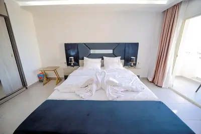 a large white bed in a room with windows at Hurghada-Scandic Resort-The Diamond Of Scandic Apartment -Sea veiw&Sandy Beach Just Downstairs in Hurghada