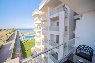a white building with the ocean in the background at Hurghada-Scandic Resort-The Diamond Of Scandic Apartment -Sea veiw&Sandy Beach Just Downstairs in Hurghada